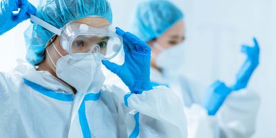 Woman health care worker putting on personal protective equipment