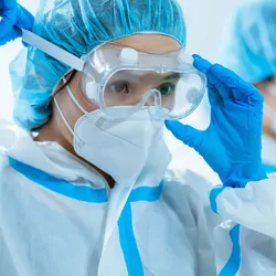 Woman health care worker putting on personal protective equipment