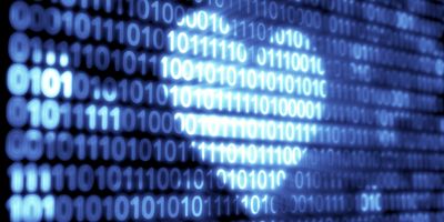 Illustration of binary code 1s and 0s against a black background colored to infer the shape of a heart
