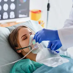Women in hospital bed with breathing mask on