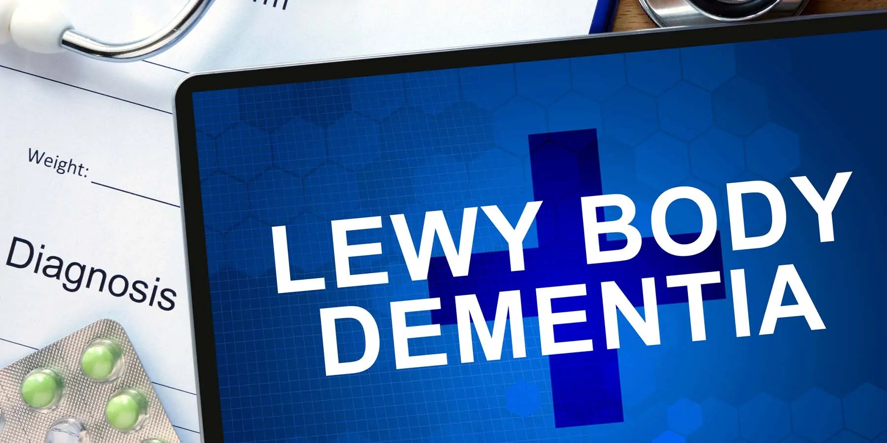 Image of a tablet with Lewy Body Demetia written on it next to a diagnosis sheet and some pills