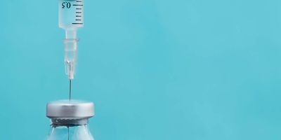 A hypodermic needle drawing liquid from a bottle