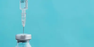 A hypodermic needle drawing liquid from a bottle