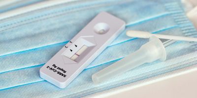 Rapid antigen test next to a swab resting on a mask