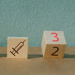 Wooden blocks with syringes on them and on block has the number 3 in red