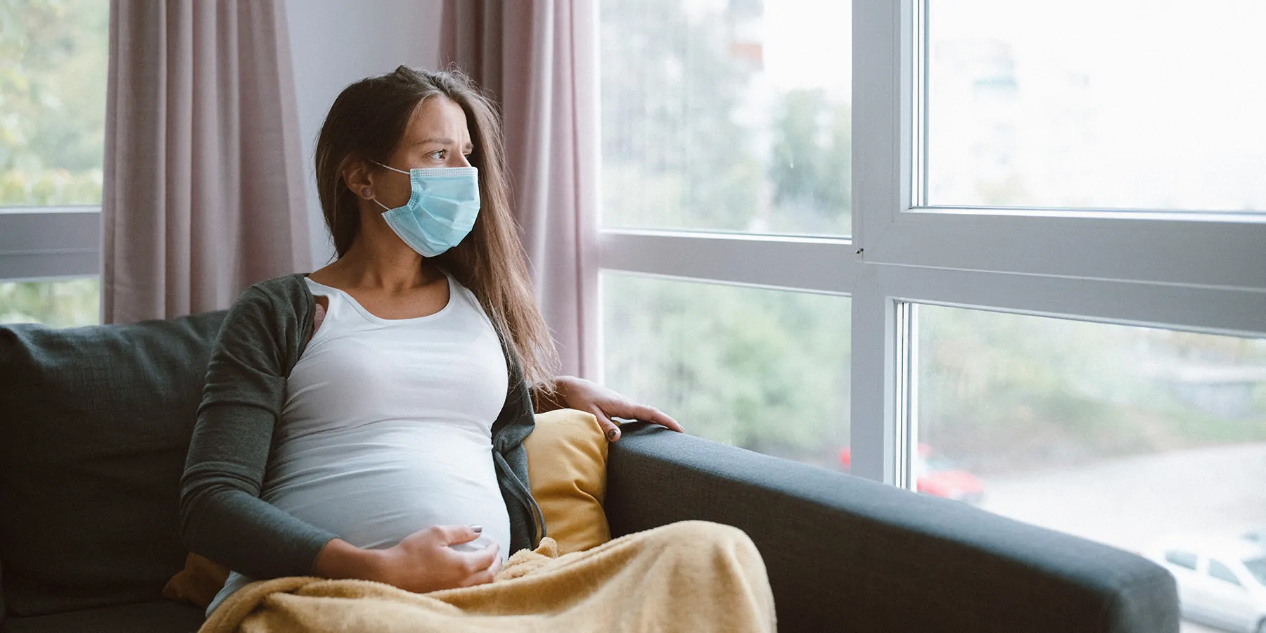 Pregnant woman looking out a window while sitting down