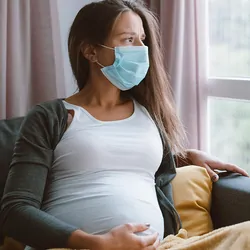 Pregnant woman looking out a window while sitting down