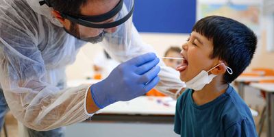 Health care professional swabing a childs mouth for a saliva sample