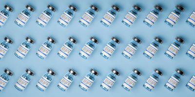 Vaccine bottles laid out on a blue background