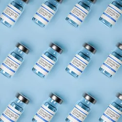 Vaccine bottles laid out on a blue background