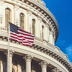 Image of the top of the Capitol building in the USA with an American flag