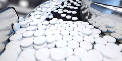 White pills being moved down a conveyor belt
