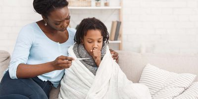 Mother checking the temperature of sick child wrapped in a blancket