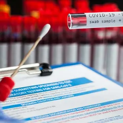 Health care provider with a COVID-19 test swab and clipboard