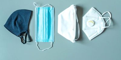 Four different face masks laid on a light blue table
