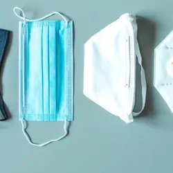 Four different face masks laid on a light blue table