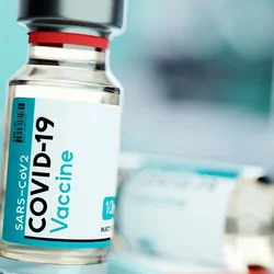 Covid vaccine bottles, one upright, one tipped over, on a table