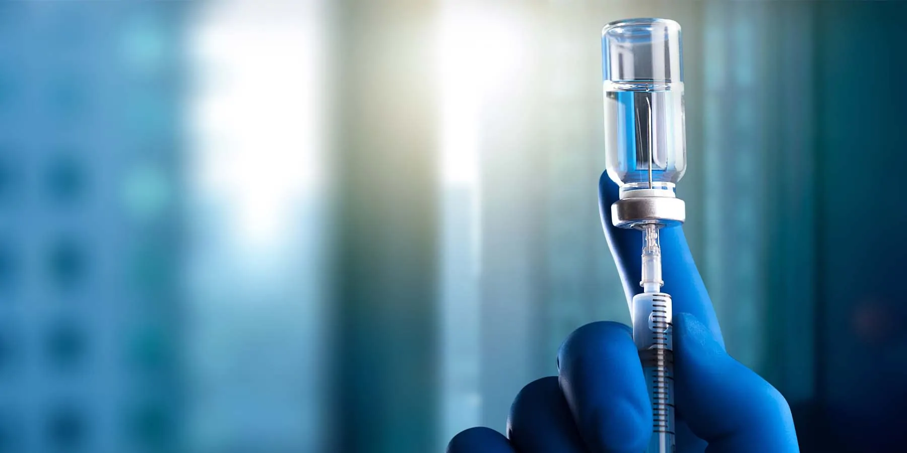 NIH Scientists Urge Pursuit of Universal Coronavirus Vaccine Gloved hand drawing liquid into a needle from a bottle
