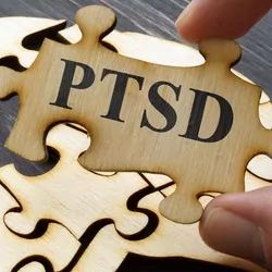 A jigsaw puzzle of a human brain with a missing piece labled PTSD