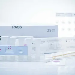 Componants of various COVID-19 testing kits resting on a white background