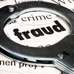Handcuffs over the word "fraud" written on a newspaper