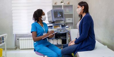 Female health care professional speaking with a pregnant women at a clinic