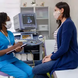 Female health care professional speaking with a pregnant women at a clinic