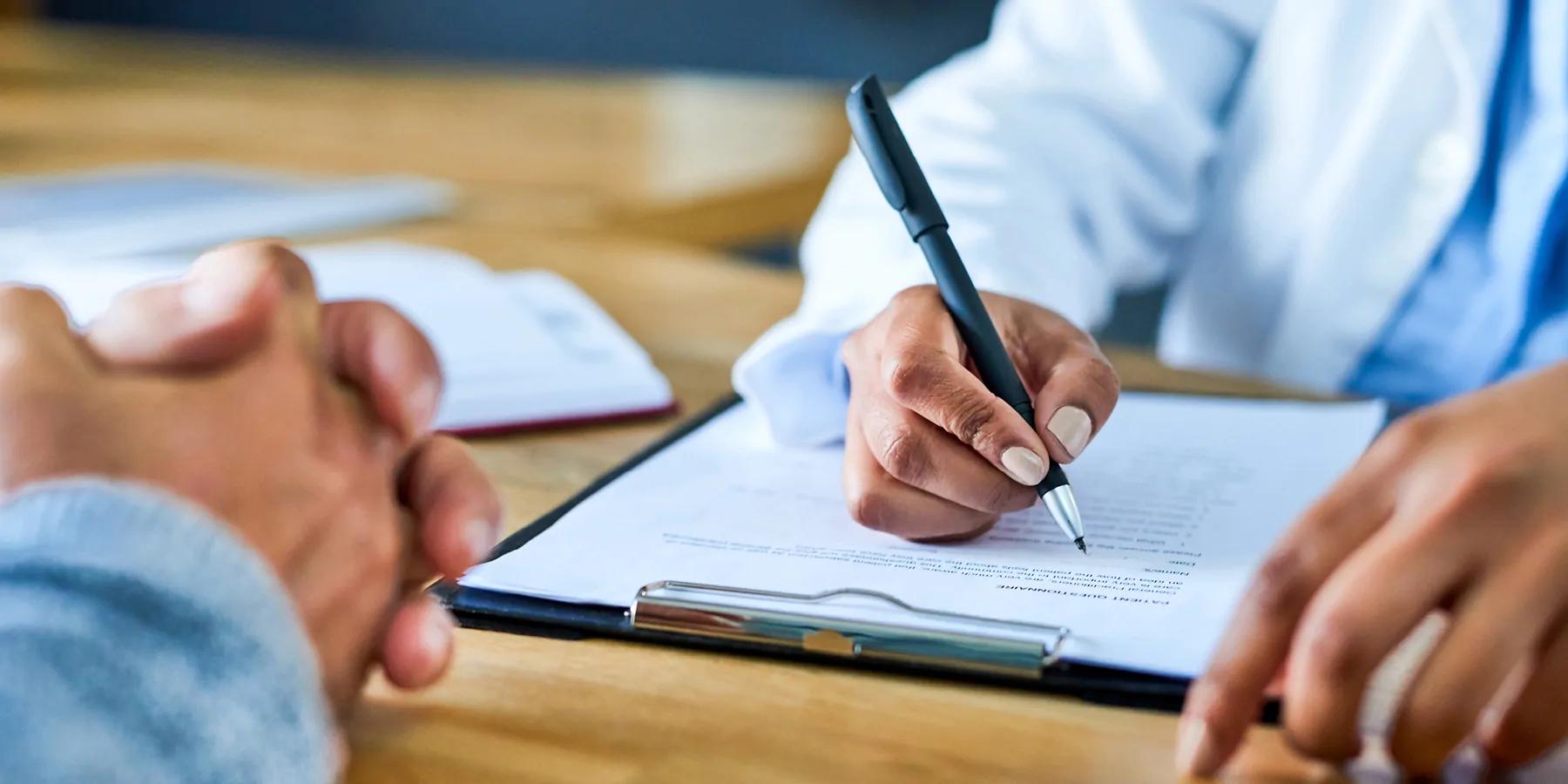 A medical professional writing in a document with another person