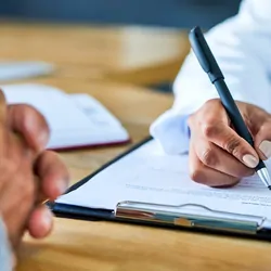 A medical professional writing in a document with another person
