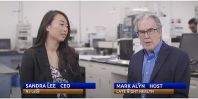 Host and co-host of the new podcast speaking to the camera with a lab in the background