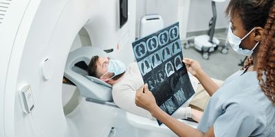 A female radiologist examines an MRI image next to the patient