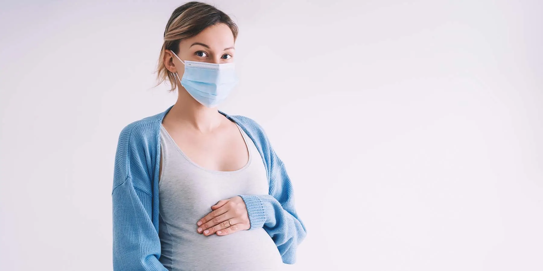 What We Know about the Ways COVID-19 Can Impact Pregnant Women and Their Babies A pregnant women wearing a mask on a white background