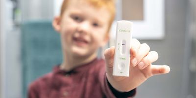 Child holding a lateral flow assay to the camera