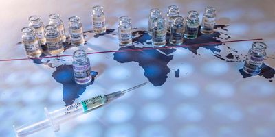 Photo of CORBEVAX vaccine vials and a syringe placed on top of a world map.