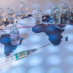 Photo of CORBEVAX vaccine vials and a syringe placed on top of a world map.