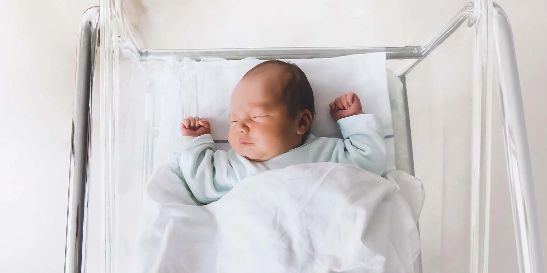 Newborn baby sleeping in a hospital crib
