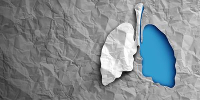 Paper lungs were one is blue and the other grey on a dark grey background of crumpled paper