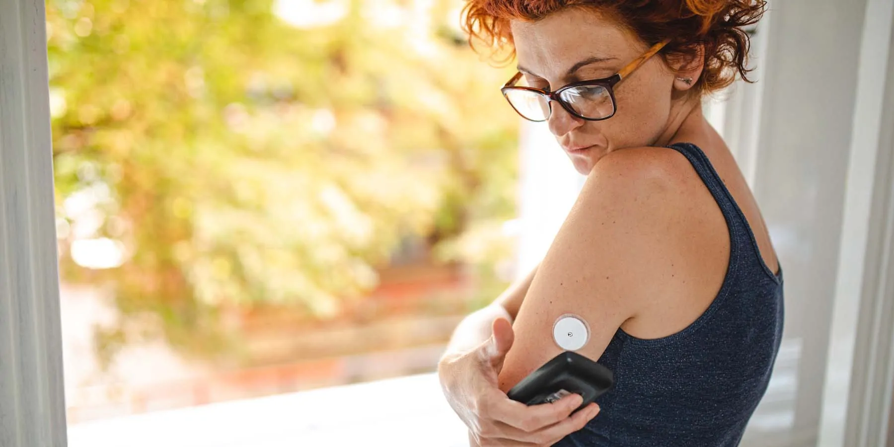 Photo of a diabetes patient using their phone to scan a continuous glucose monitoring device.