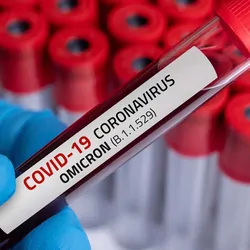 Gloved hand holding a vial ov blood labeld as being positive for Omicron variant