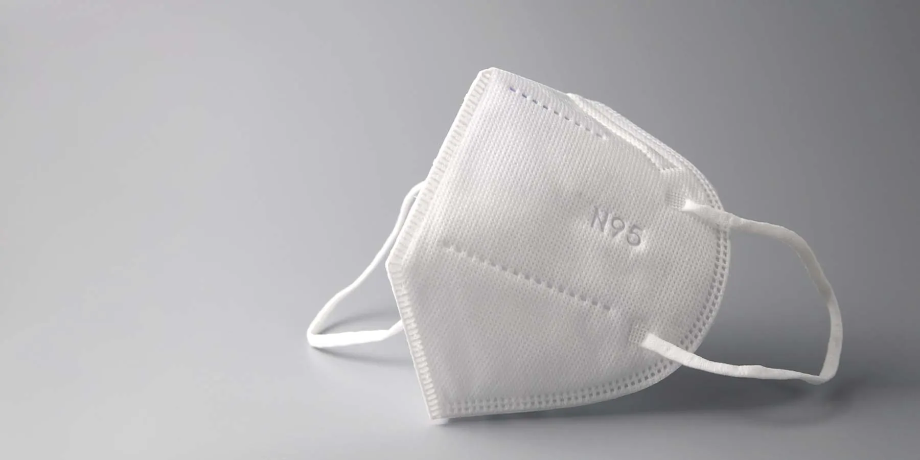 An N95 mask on a grey background