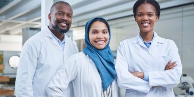 Photo of a Black man and a woman wearing a hijab wearing white lab coats in the clinical lab.