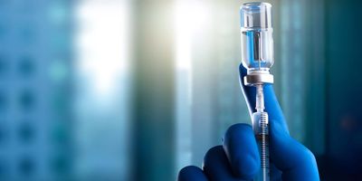 Gloved hand drawing a vaccine into a syringe 