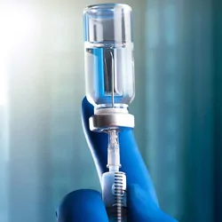 Gloved hand drawing a vaccine into a syringe 