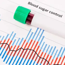 Blood sample in tube resting on a blood sugar test result page