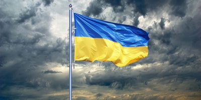Photograph of the Ukrainian flag dramatically flying with a storm brewing in the background.