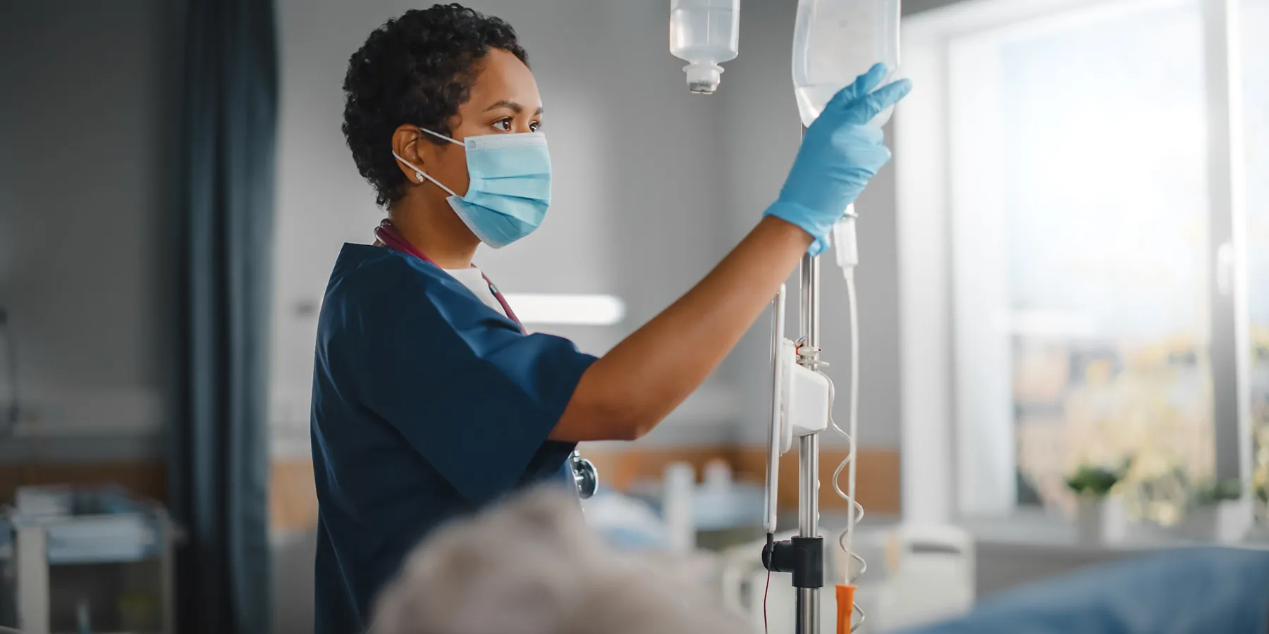 Female health care provider checking medication and IV in patient