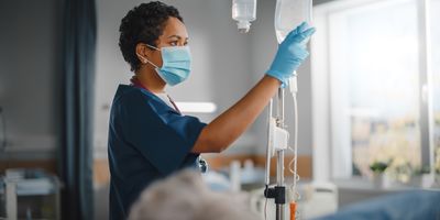 Female health care provider checking medication and IV in patient