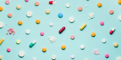 Photograph of different pills and pharmaceuticals spaced out in a grad on a blue background.