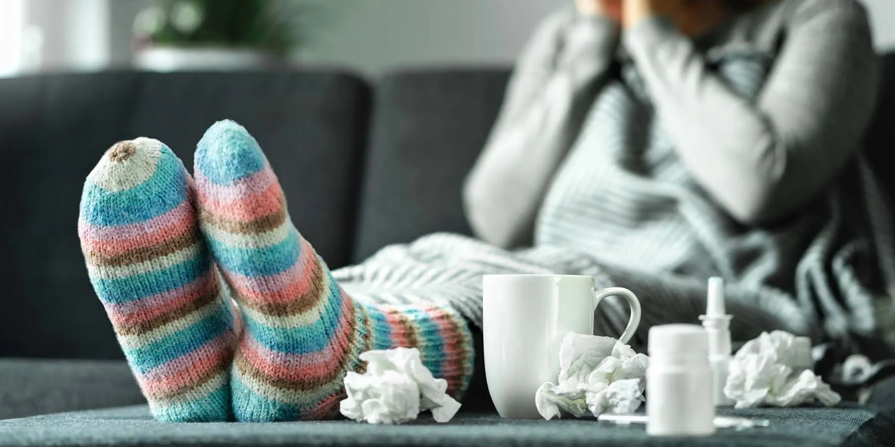 Person sitting on couch at home, sick with the flu