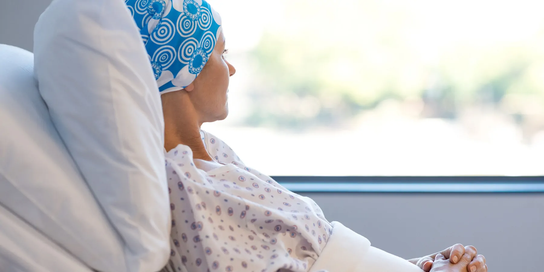 Cancer patient laying in hospital bed, looking out the window